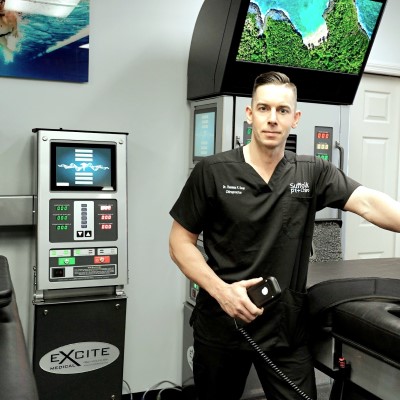 Picture of a Dr. Thomas Dow standing in front of the DRX9000 machine for lumbar spinal decompression therapy in Commack, NY